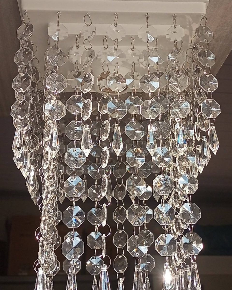 Detalhe de um lustre de cristal acrílico com fios de contas e pingentes em gota