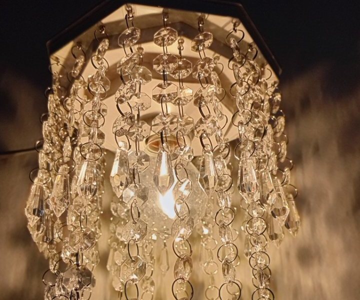 Lustre octogonal aceso, com luz quente atravessando o cristal